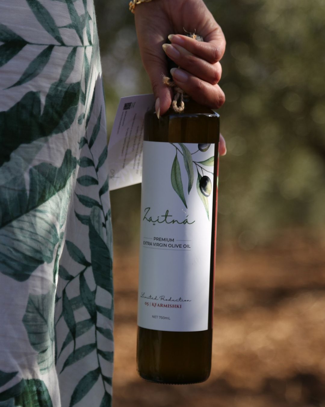 A 750 mL bottle of Zaitná carried through the olive grove